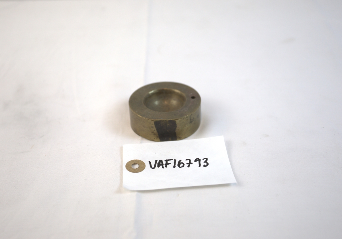 Sirkelformet metallgjenstand med fordypning.