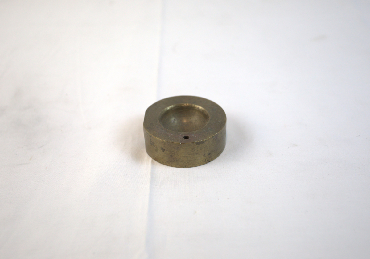Sirkelformet metallgjenstand med fordypning.