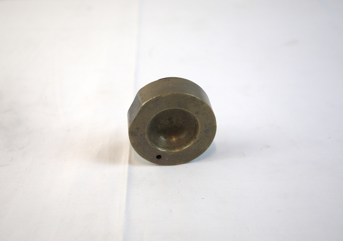 Sirkelformet metallgjenstand med fordypning.