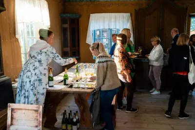 Besøkende samlet rundt bord med servering i et historisk interiør.
