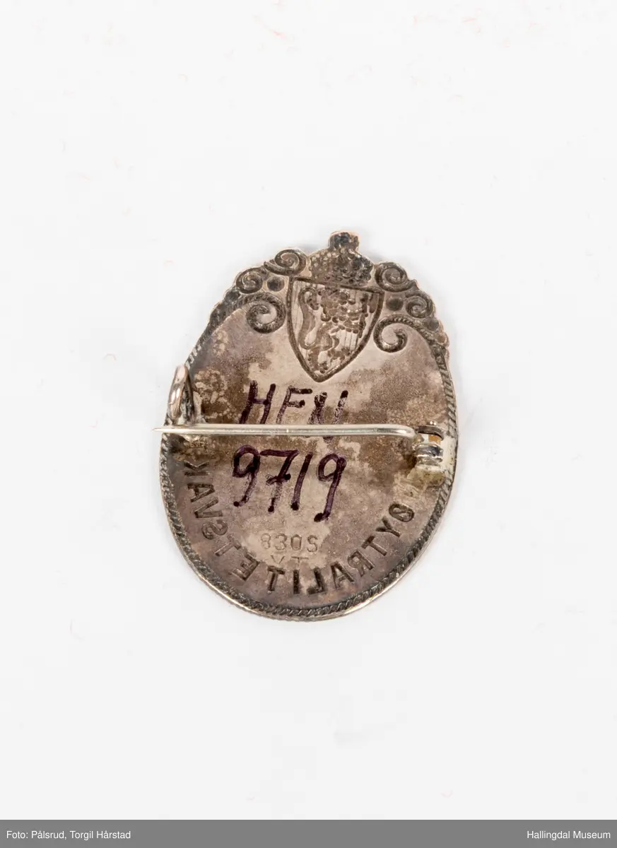 Nøytralitetsvaktmerke, 1940. Tilhørt Leif Levorsen med nummer 12947. Merket har en oval form med en bord som er ornamentert rundt riksvåpnet øverst. Navn og nummer står i midten.