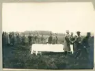 Prisutdelning på ett regndisigt övningsfält. Kronprins Gustaf Adolf (?) delar ut pris.
Trol. I11,
