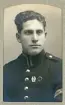 En ung man i uniform (korpral) med förtjänstmärken. 
Bröstbild, halvprofil. Ateljéfoto.