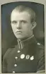 En ung man i uniform (m/95) med förtjänstmärken.
Bröstbild, halvprofil. Ateljéfoto.