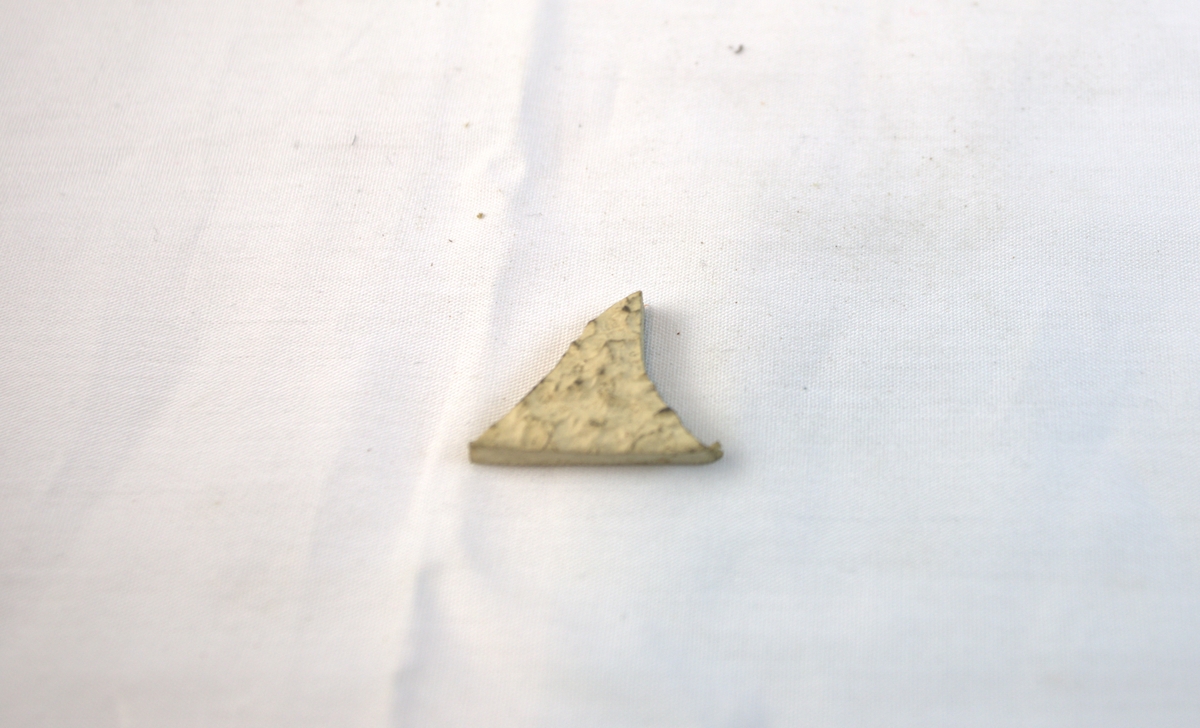 Trekantformet gjenstand i lett materiale.