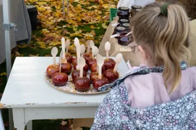 En jente står foran et fat med glaserte epler på høstmarkedet. 