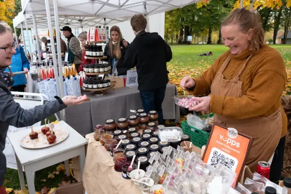 En kvinne får en smaksprøve fra en markedsbod på høstmarkedet på Eidsvoll 1814. 