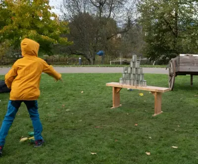 En kutt kaster erteposer på blikkbokser. 