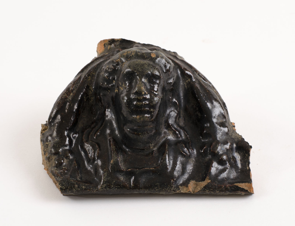 Reliefmönstrat med växtdekor samt människofigur, svartglaserat.