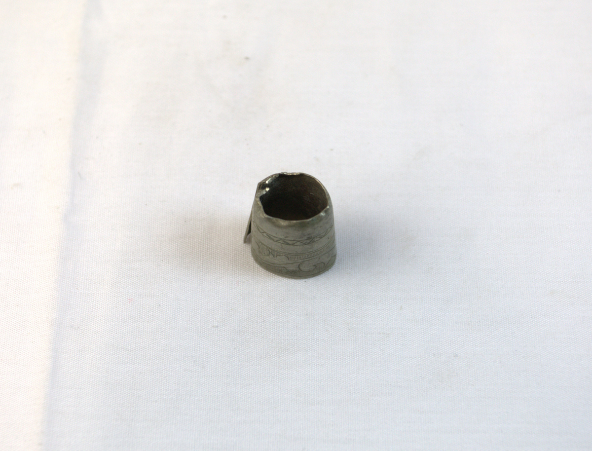 Gjenstand i tynt metall. Metallet har mønser og bøyd i en sirkelform.