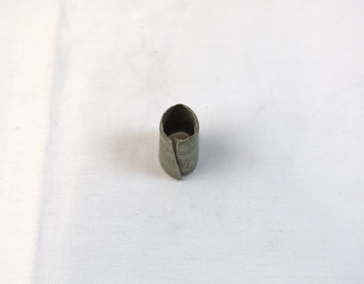 Gjenstand i tynt metall. Metallet har mønser og bøyd i en sirkelform.