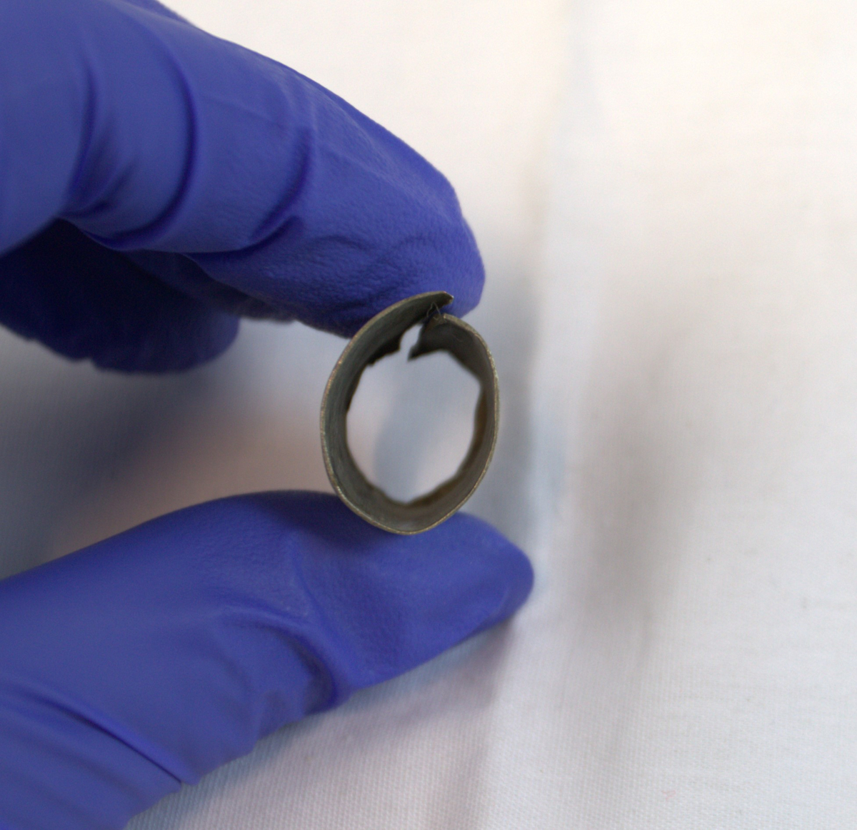 Gjenstand i tynt metall. Metallet har mønser og bøyd i en sirkelform.