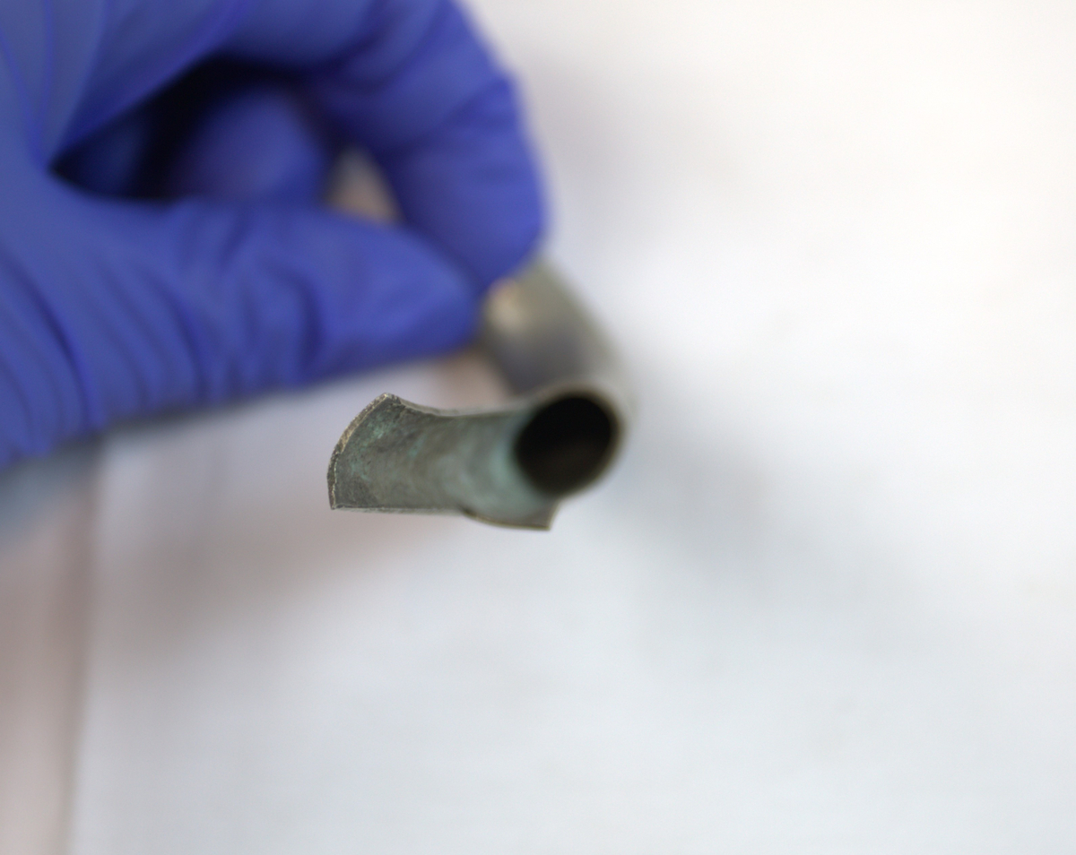 Metallrør som er buet og klippet med tre hakk i den ene enden.