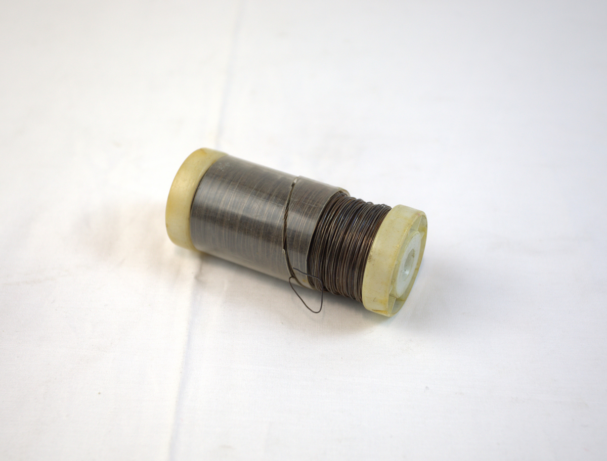 Ståltråd med bakelittsnelle. Det er også et gjennomsiktig plast/bakelitt-deksel rundt metalltråden.