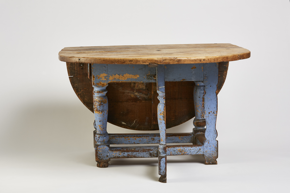 Bordets plate og 2 sideklaffer er satt sam- men av 3 bord og sammenføyet m/triangler. Klaffene er festet m/hengsler og nagler og forsterket med nye beslag. Understellet består av 4 dreide stolper, 2 er halvert og kan slåes ut som støtt under gulvet. I sargen er det en skuff.
Rektangulær b.plate m/halvsirkelformede klaffer.