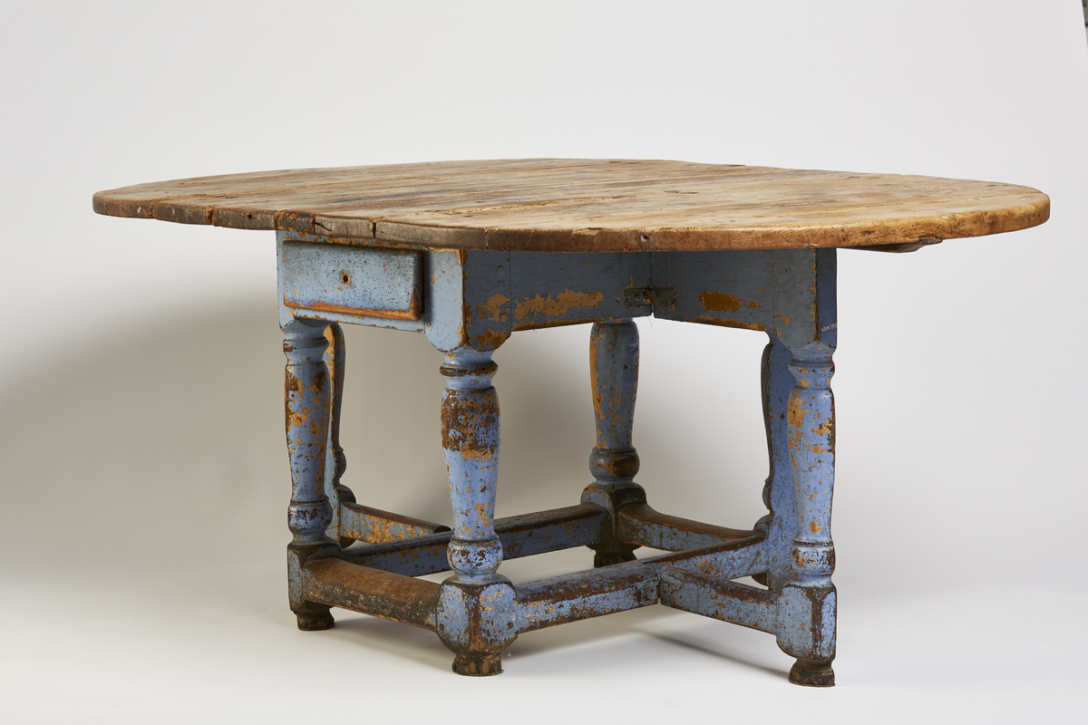 Bordets plate og 2 sideklaffer er satt sam- men av 3 bord og sammenføyet m/triangler. Klaffene er festet m/hengsler og nagler og forsterket med nye beslag. Understellet består av 4 dreide stolper, 2 er halvert og kan slåes ut som støtt under gulvet. I sargen er det en skuff.
Rektangulær b.plate m/halvsirkelformede klaffer.