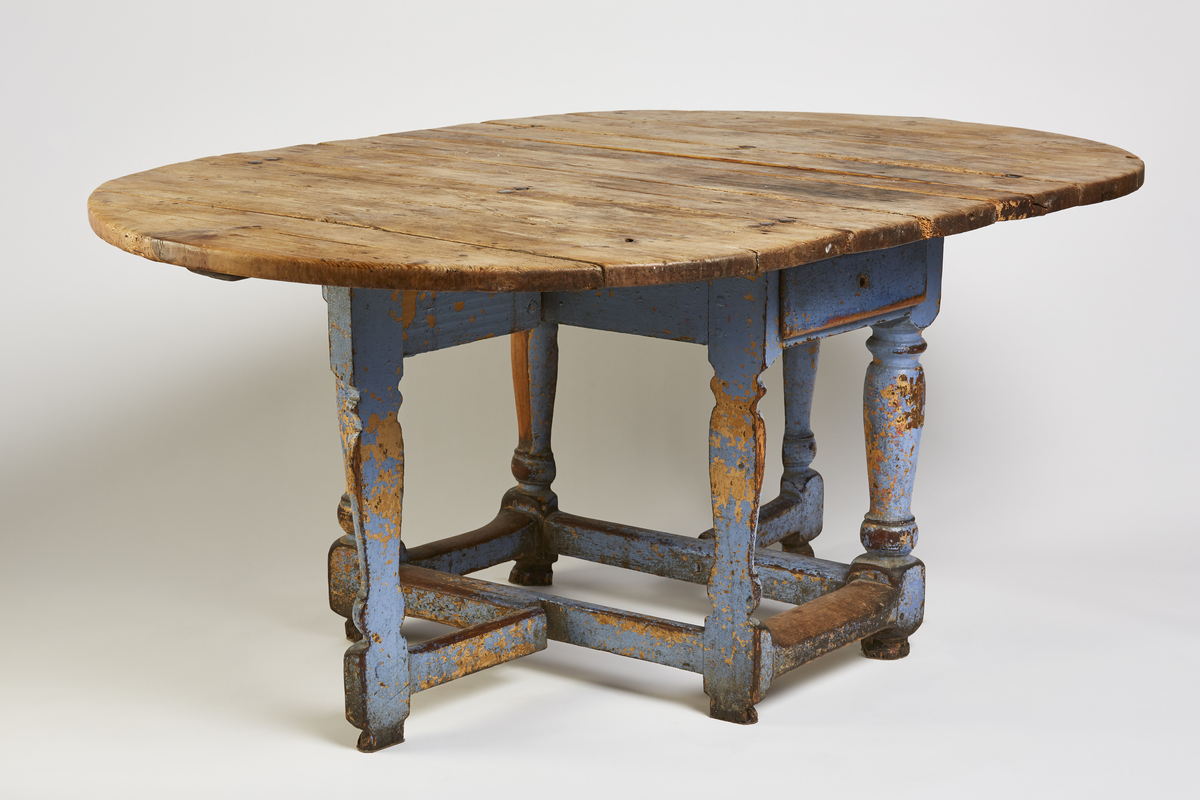 Bordets plate og 2 sideklaffer er satt sam- men av 3 bord og sammenføyet m/triangler. Klaffene er festet m/hengsler og nagler og forsterket med nye beslag. Understellet består av 4 dreide stolper, 2 er halvert og kan slåes ut som støtt under gulvet. I sargen er det en skuff.
Rektangulær b.plate m/halvsirkelformede klaffer.