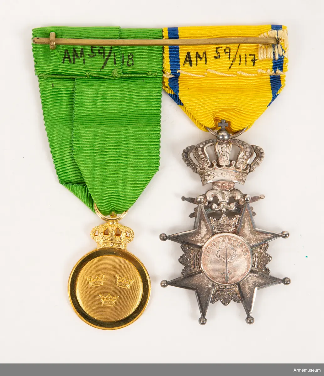 Grupp M II.
Svärdsmannatecken med band tilldelat styckjunkaren Georg Wilhelm Wessman.  Ett snedställt johannitkors av silver. Åtta uddar, var och en slutande i en kula. Mellan korsarmarna öppna kronor. På åtsidan har tecknet en blå, emaljerad glob i korstets mitt med ett stolpvis ställt svärd och tre öppna kronor ställda två och en. Mellan korsets övre vänstra udd och övre högra störtande svärd. Frånsidans mittglob är av silver med ett stolpvis ställt svärd omlagt med två kvistar ovanför "PRO PATRIA". Tecknet hänger i en kunglig krona. Medaljband av ett 35 mm brett sidenripsband - gult med mörkblå kantrand. 