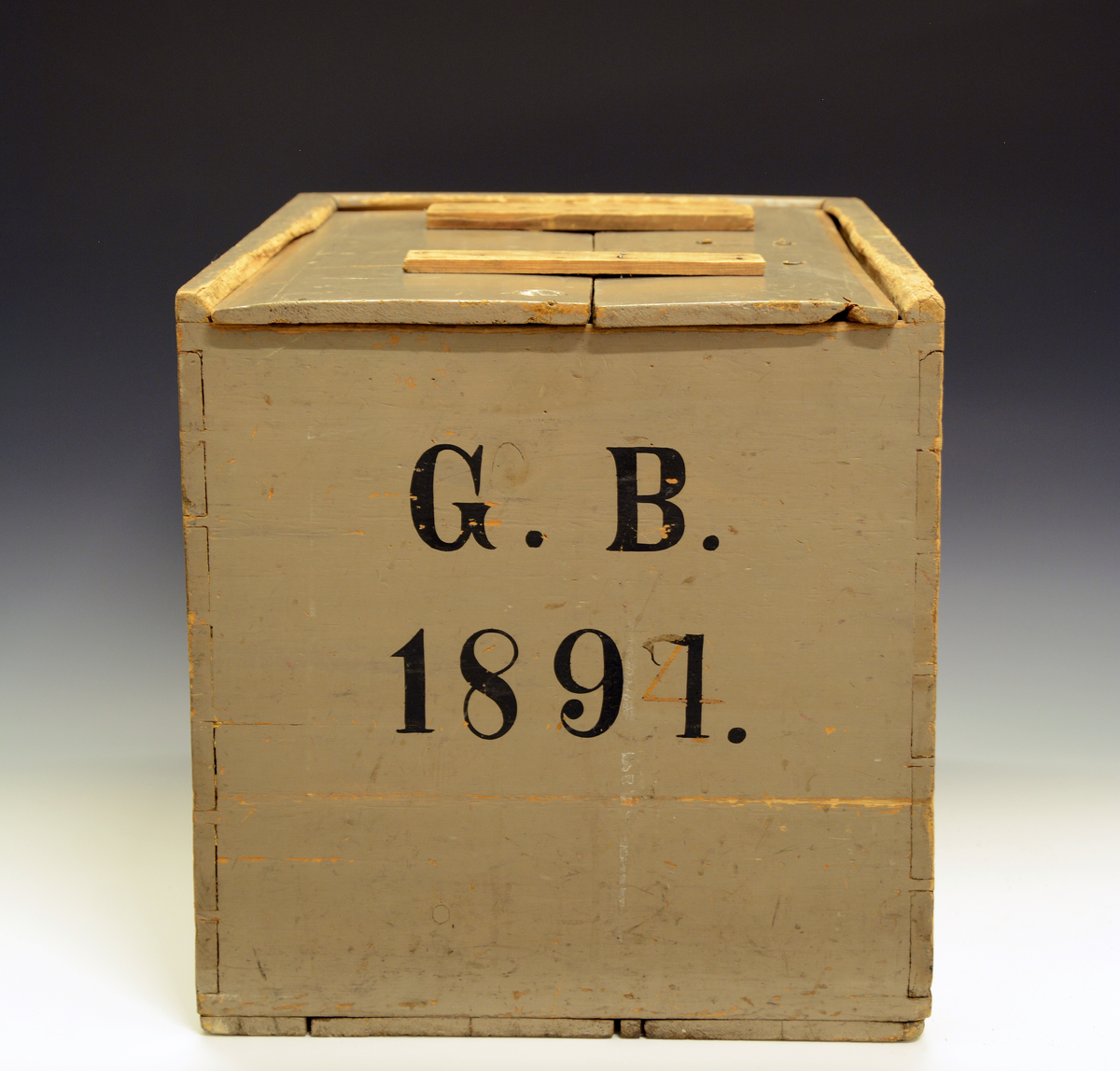 Kasse med skyvelokk. Furu. Sinket. Gråmalt med initialer "G.B. 1891" på enden. B står for Bärnholdt. Skal ha blitt brukt som skipskiste ombord i seilskute.