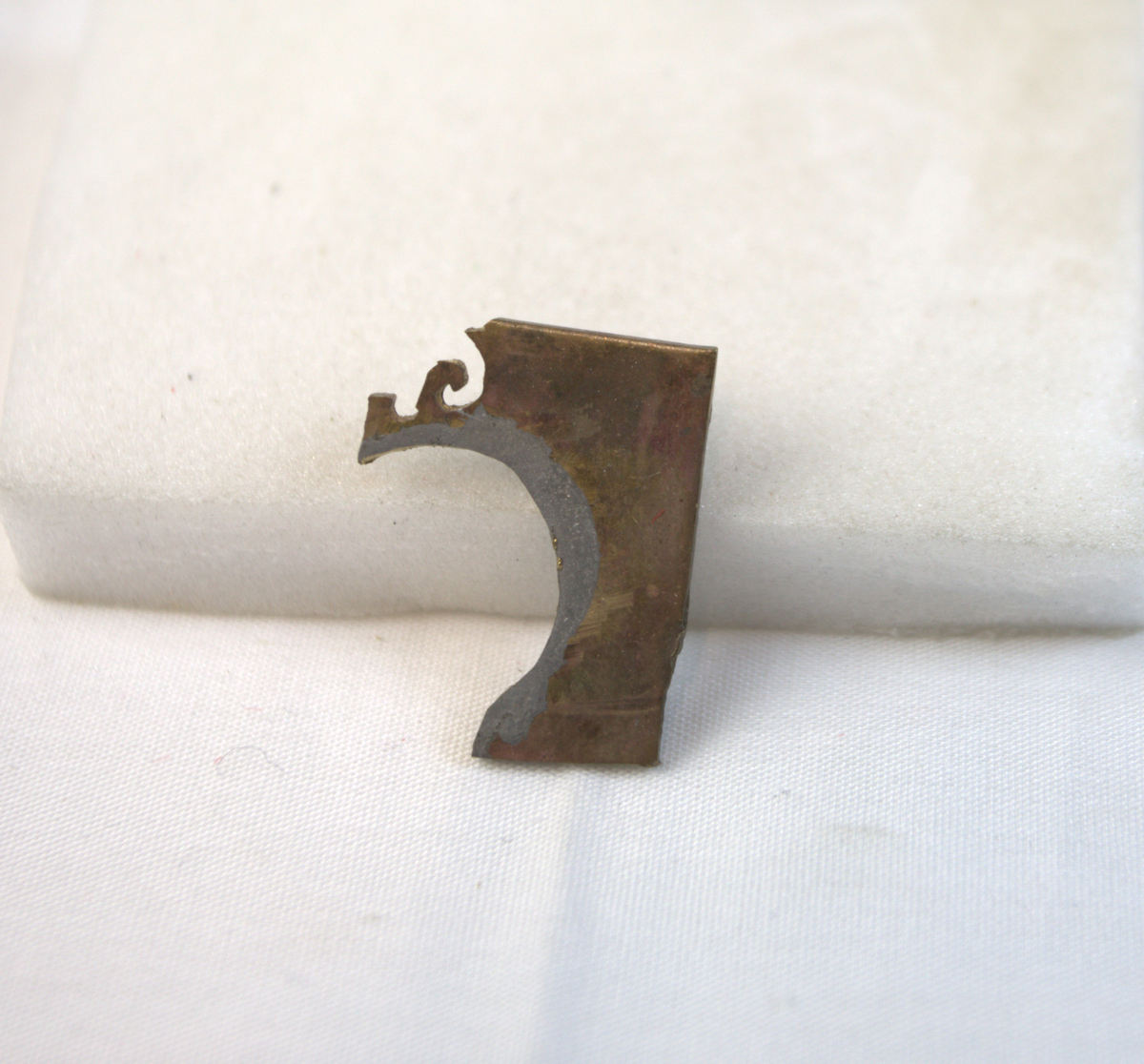 Flat metallgjenstand med spor etter skjæring. 