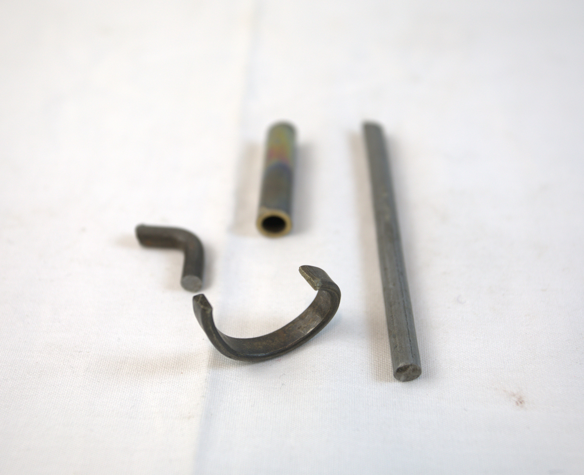 Fire metallgjenstander. To av dem er bøyd, en er avlang og rett, mens en er rørformet.