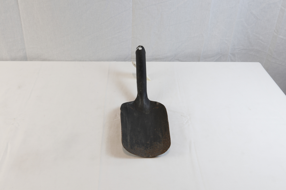 Spade til bøtte til å bære koks i. Spaden er noe rusten og har et hull på enden av håndtaket. 