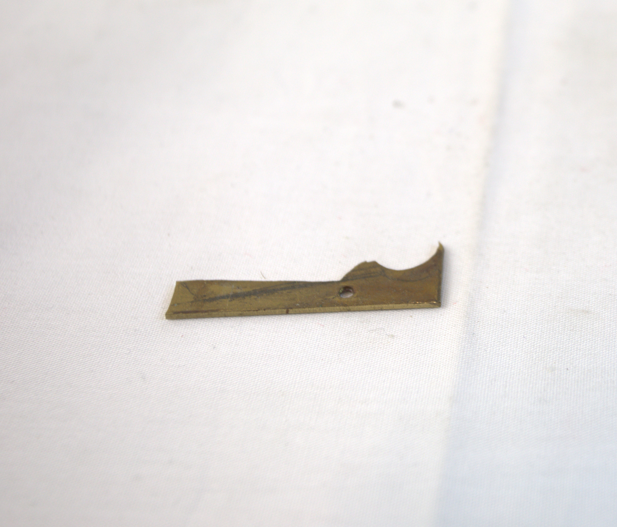 Metallgjenstand i rød- og gullfarge. Trolig brukt som materiale i gullsmedvirksomhet.