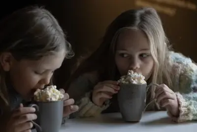 To jenter drikker kakao med krem.