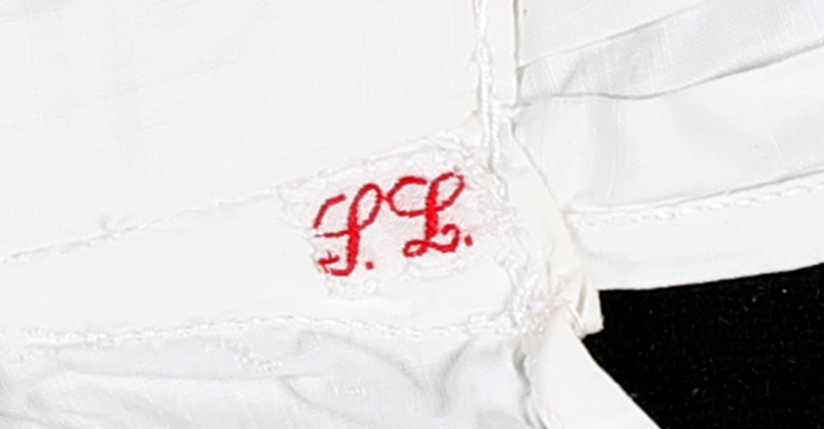 Forkle med påsydd blondekant nederst. Nedkanten på forkleet går opp i en spiss på midten.