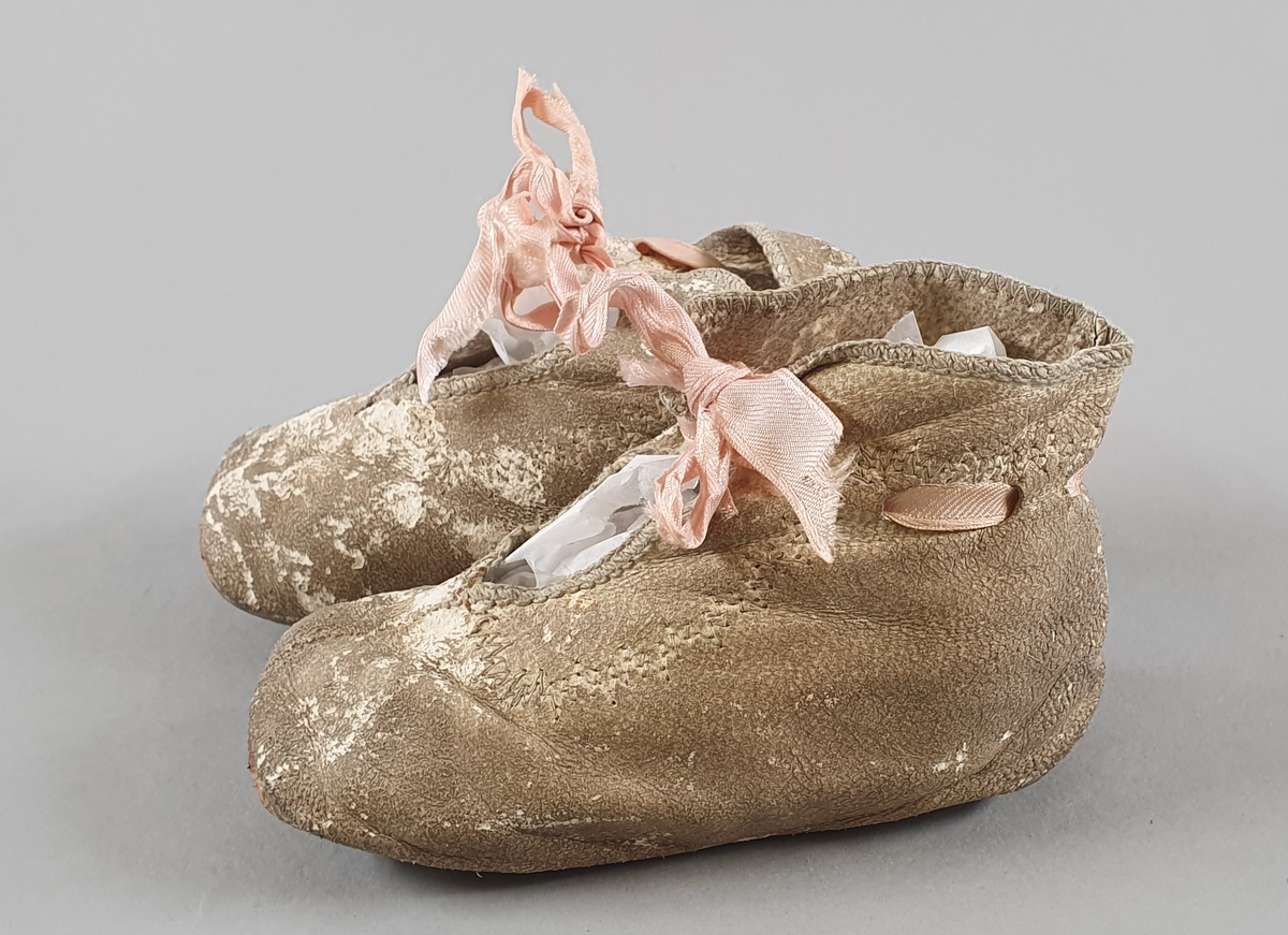 Babysko av skinn med rosa sløyfe.