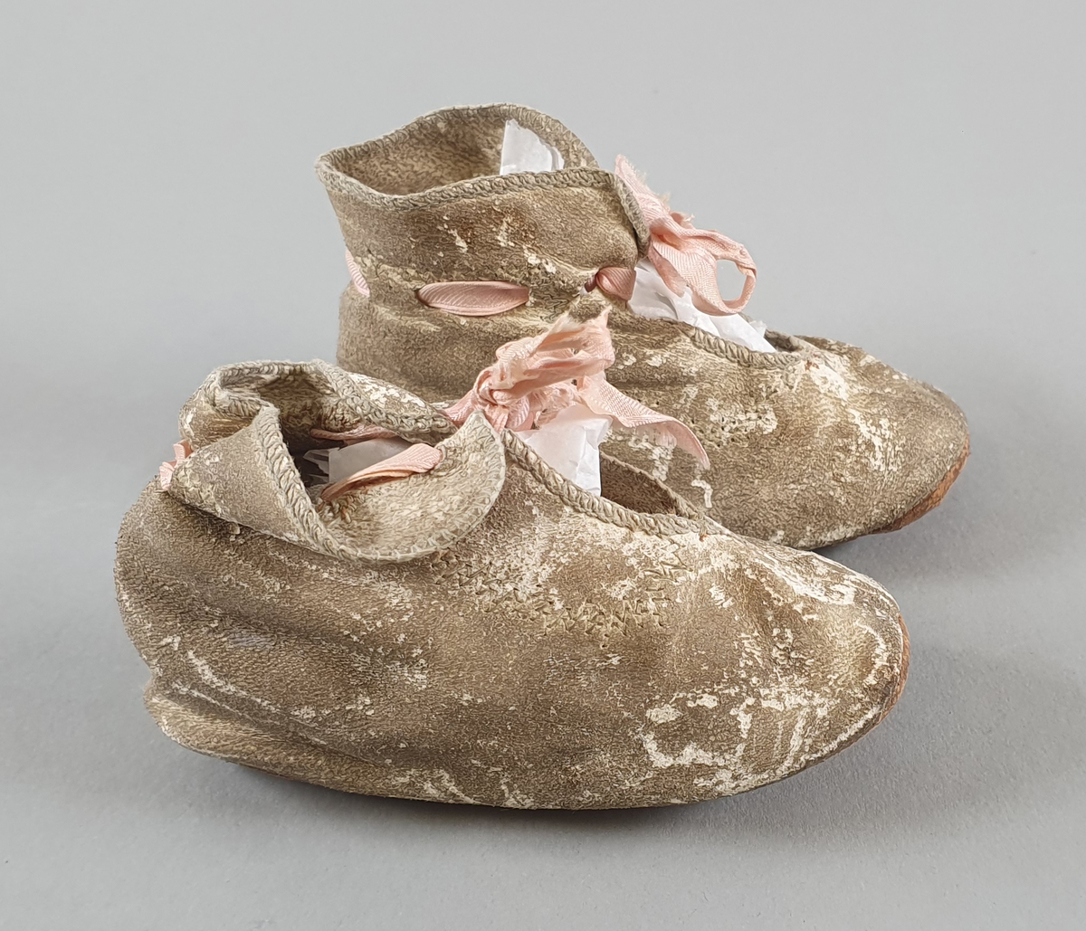 Babysko av skinn med rosa sløyfe.