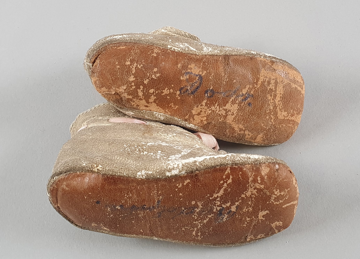 Babysko av skinn med rosa sløyfe.