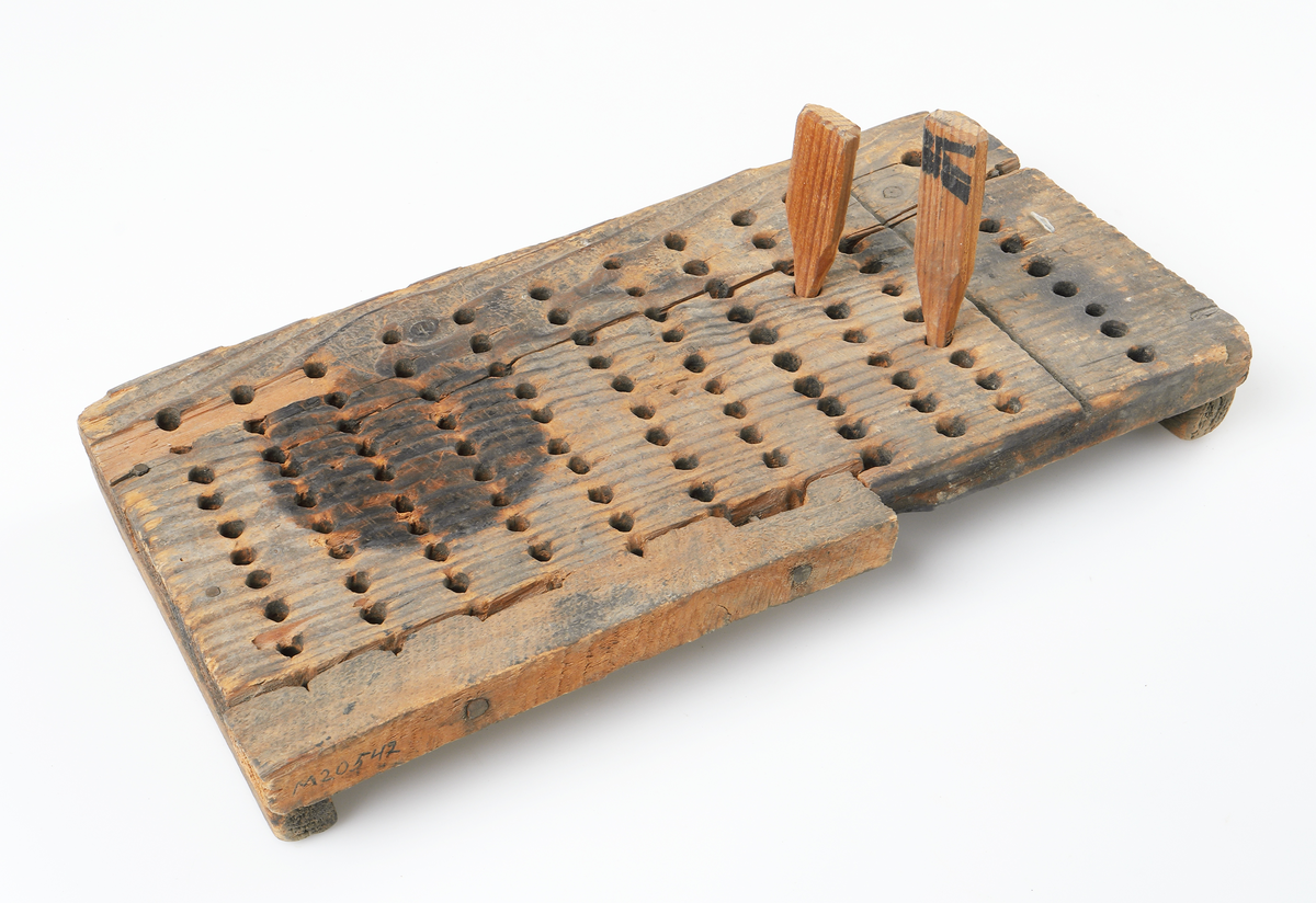 Räknebräda av trä bestående av en rektangulär 
bräda, som är skadad i ena kanten. Överst finns 
10 hål för hundratal och underst 10x10 hål för en-
tal. Som räknesticka användes en träpinne och 
en glaspinne. Båda saknas. 
Invent. 2006-07-27.
Inskriven i huvudkatalogen 1968
Funktion: Att räkna de tillverkade glasen i hyttan