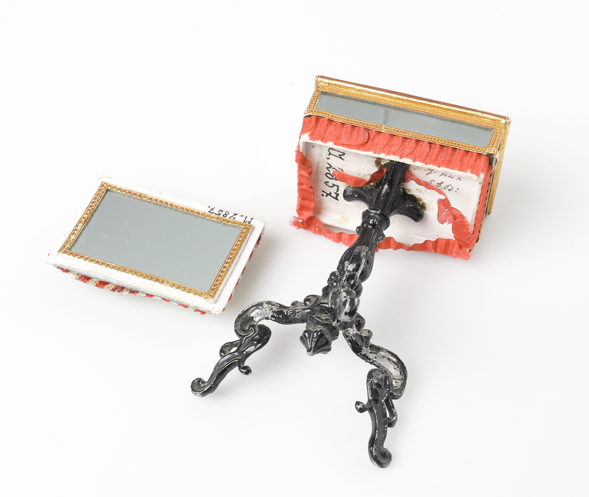 Nåldyna, på fotställning av metall, prydd med speglar.