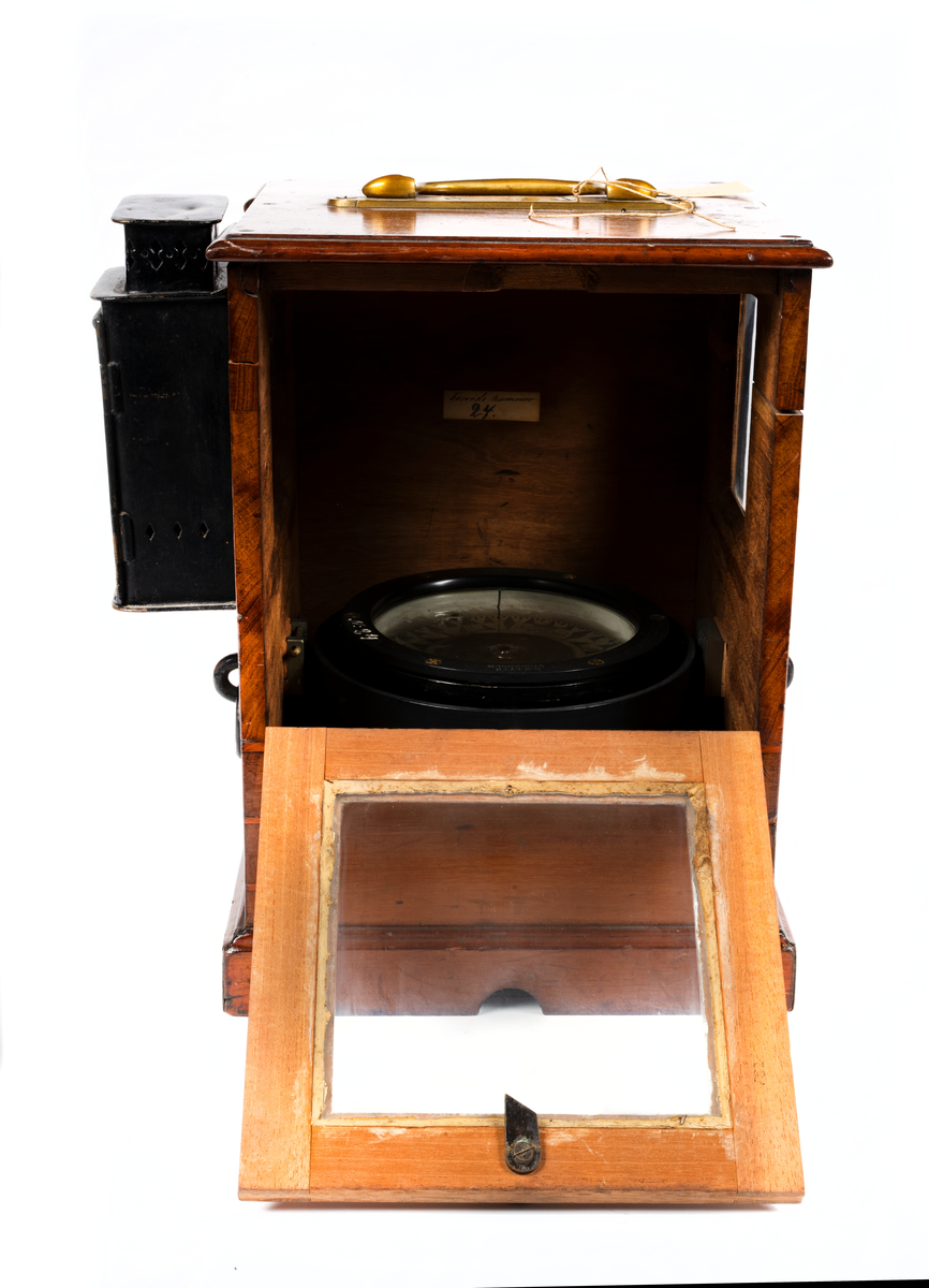 Båtkompass med nakterhus av mahogny. Kompass, sprit, märkt: "G.W. Lyth, Stockholm 7381", samt med vit färg "N. 24" (förrådsnummer). 
Ros streckindelad, märkt: "Patent Lemcke. G.W. Lyth. Stockholm". Nakterhus, fyrkantigt, med dörr. Fäste för 2 lanternor.
Märkt med vit färg "24".