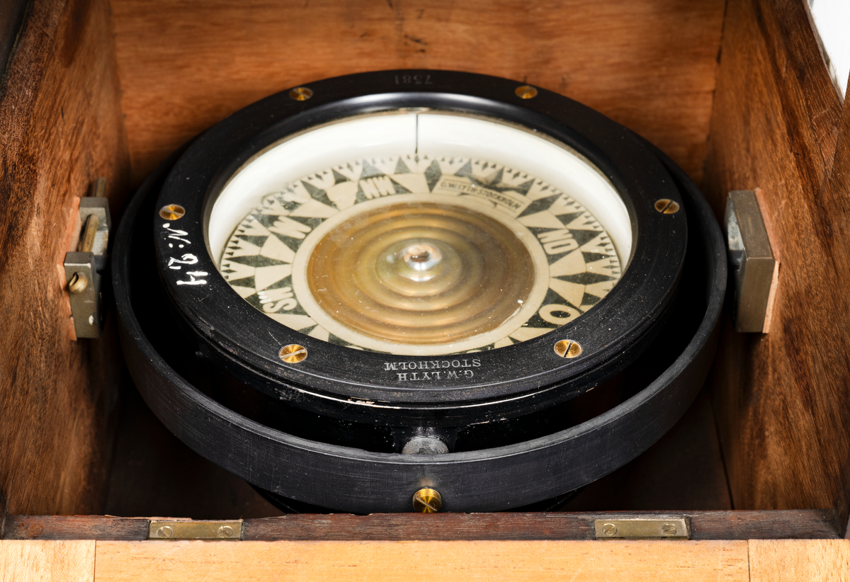 Båtkompass med nakterhus av mahogny. Kompass, sprit, märkt: "G.W. Lyth, Stockholm 7381", samt med vit färg "N. 24" (förrådsnummer). 
Ros streckindelad, märkt: "Patent Lemcke. G.W. Lyth. Stockholm". Nakterhus, fyrkantigt, med dörr. Fäste för 2 lanternor.
Märkt med vit färg "24".