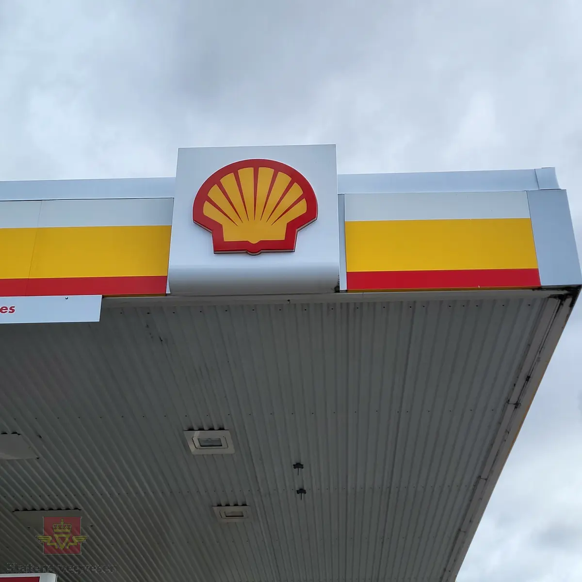 Skiltkasse med lokk. Den har led-belysning innvendig, med Shell-logo på forsiden. I hovedsak lagd av plast og aluminium, flerfarget.