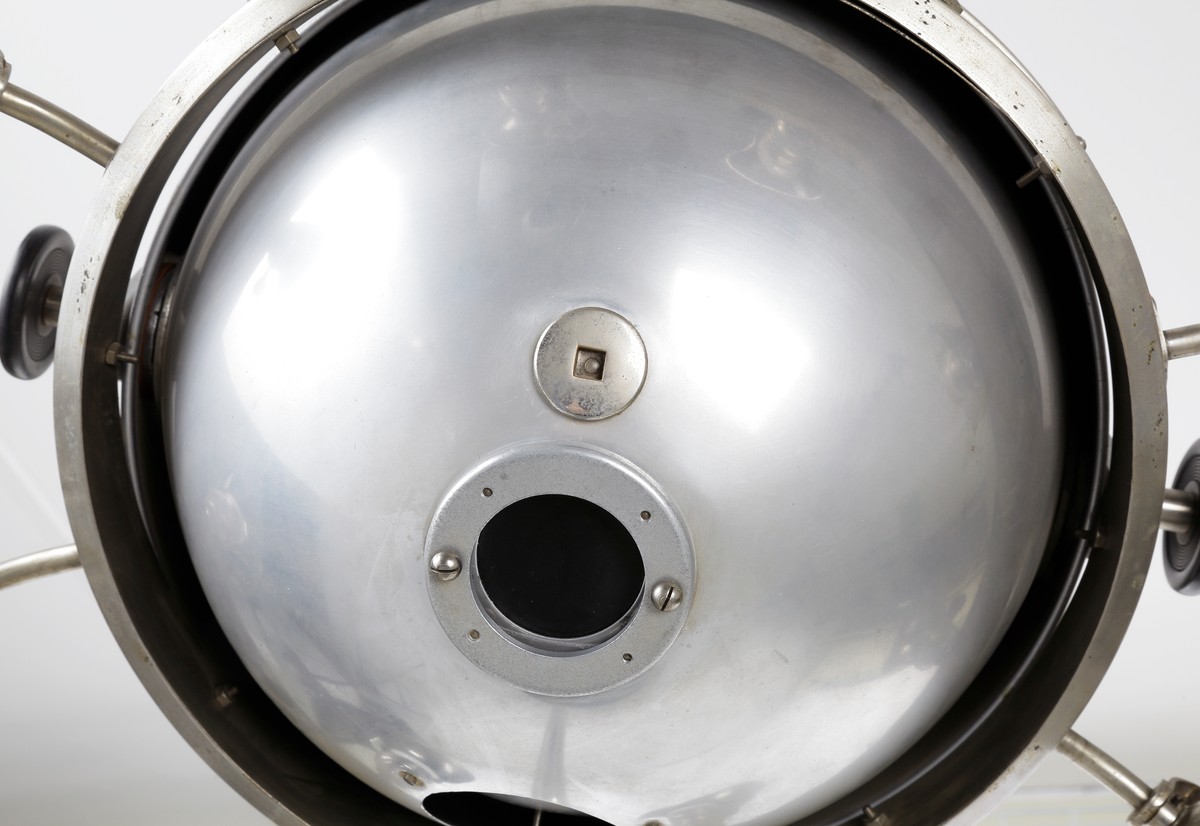 Kvartslampa som består av en förnicklad pelare med en höj- och sänkbar lampa. Lampan har ett klot vars innehåll  är en kvartslampa med kvicksilver som bildar UV-ljus. Huven har en öppningsbar del som kan öppnas med en låsbar ratt på ena sidan så själva lamphuset kan kommas åt. Denna öppningsbara del har en vridbar skiva med hål i olika storlek, 15-ca. 45mm, detta så att man kan ha olika koncentration på ljusstrålen. På andra sidan finns en motsvarande ratt som man kan justera själva kvartslampan. Runt om klotet sitter åtta stycken skärmförsedda lamphållare där varannan lamphållaren har en vridströmbrytare så att varanna lampa kan släckas. Dessa lamphållare har lampfästen i vitt porslin, och vridströmbrytarna är troligen i bakelit. Det sitter även två stycken elkontakter i porslin på klotets utsida. Foten på lampan består av en cirkelformad svartlackerad välvd platta med tre stycken vridbara dubbelhjul. På huvens utsidan sitter även två tillverkarskyltar fastnitade som har texten "QUARZLAMPEN-GESELLSCHAFT m.b.H. HANAU No. 38673, 7,8/3,8 Amp. 110/220 Volt." och "KÜNSTLICHE HÖHENSONNE QUARZLAMPEN-GESELLSCHAFT HANAU".