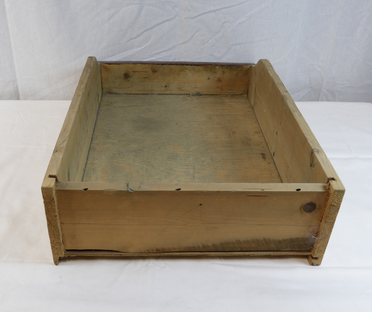 Skuff i tre, delvis rødmalt. Skuffen har blitt brukt til oppbevaring av gjenstander i gullsmedvirksomhet.