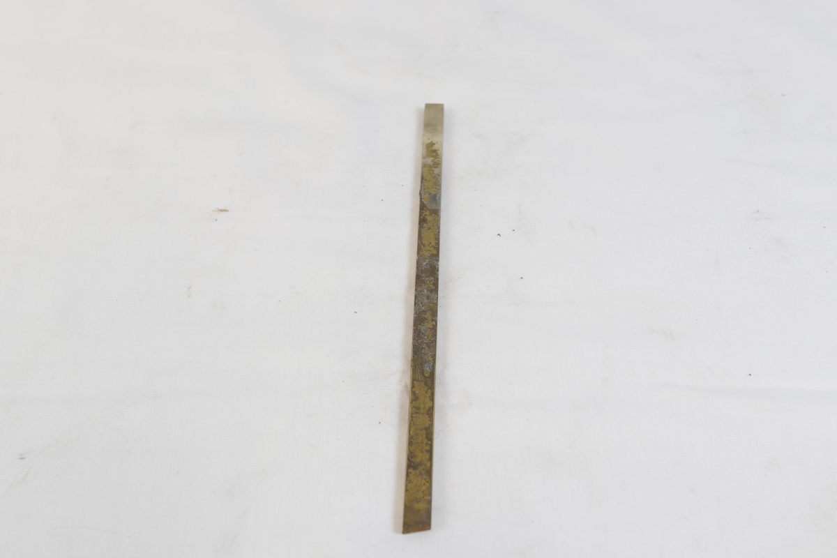 Avlang og oksidert metallgjenstand. Trolig brukt som materiale i gullsmedvirksomhet.