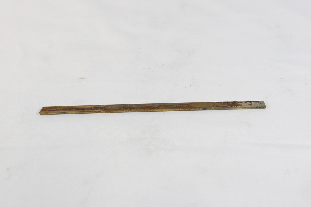 Avlang og oksidert metallgjenstand. Trolig brukt som materiale i gullsmedvirksomhet.