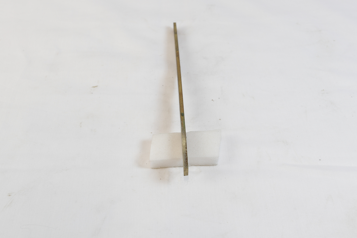 Avlang og oksidert metallgjenstand. Trolig brukt som materiale i gullsmedvirksomhet.