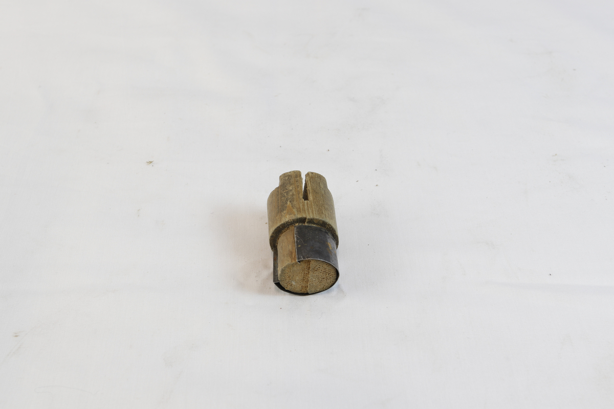 Sirkelformet tregjenstand med metallplate som delvis går rundt. 