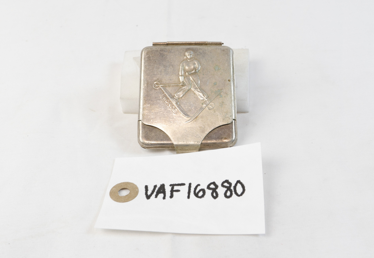 Etui i sølv med figur på ski. Etuiet var trolig opprinnelig brukt til oppbevaring av sigaretter. 