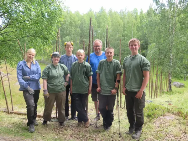 Gruppe ungdomar og ein vaksen mann står foran ein skigard