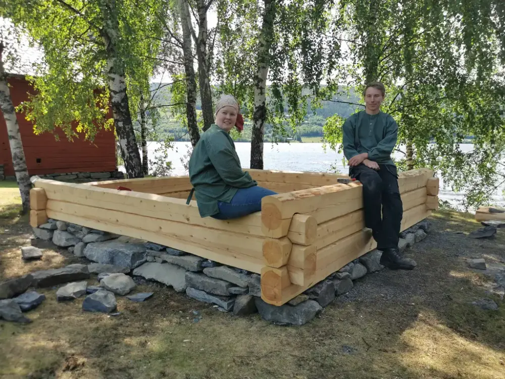 To gutar sitter på ei sandkasse i laft