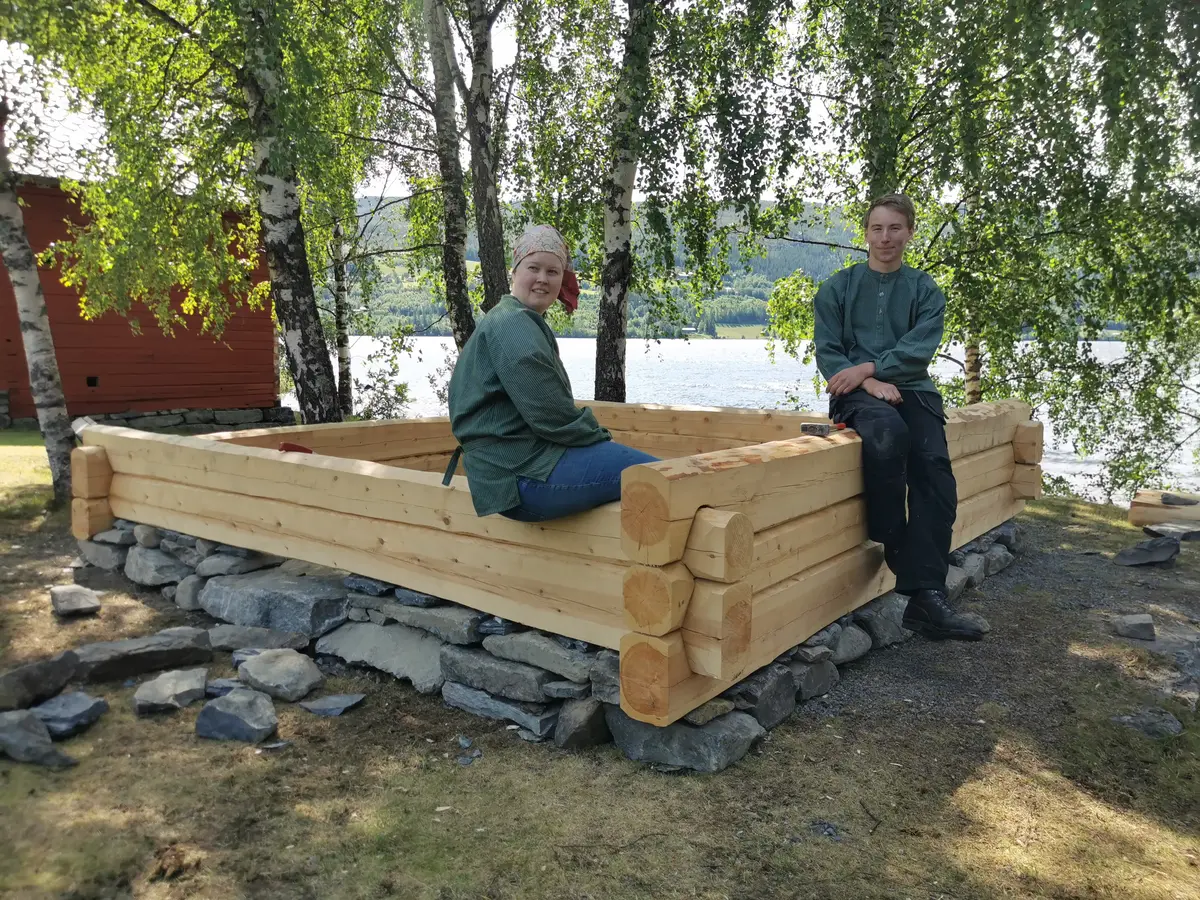 To gutar sitter på ei sandkasse i laft