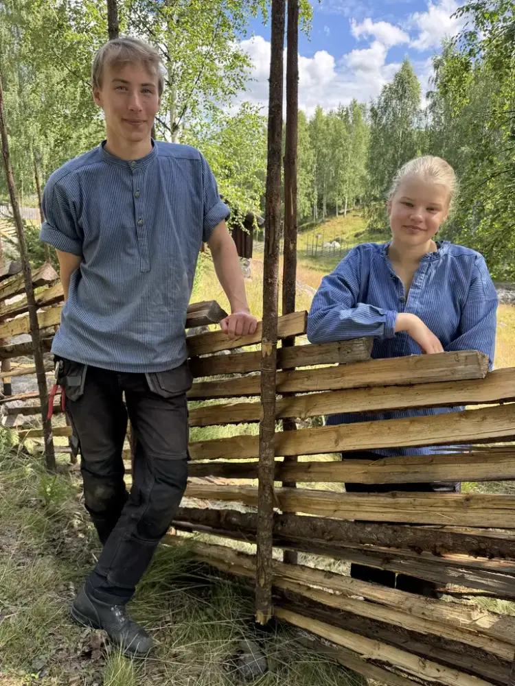 Ein gut og ei jente står ved ein skigard