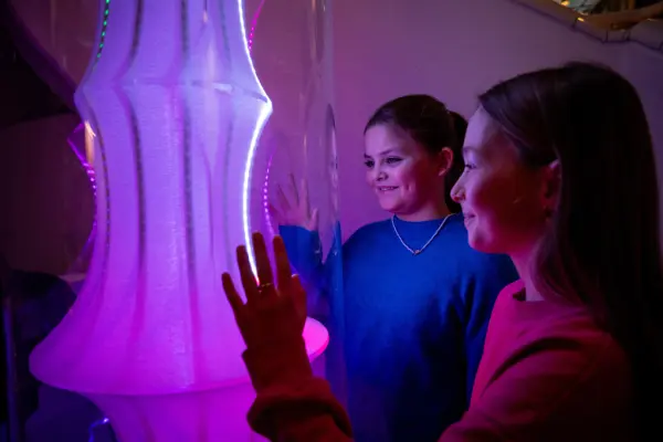 To ungdommer holder hånden opp mot lysinstallasjon