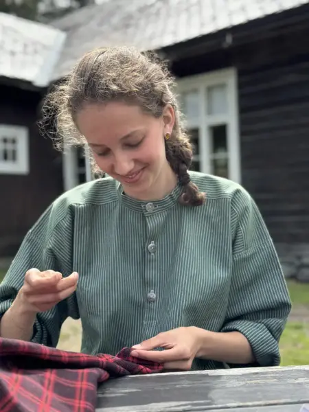 Jente i grøn busserull som syr